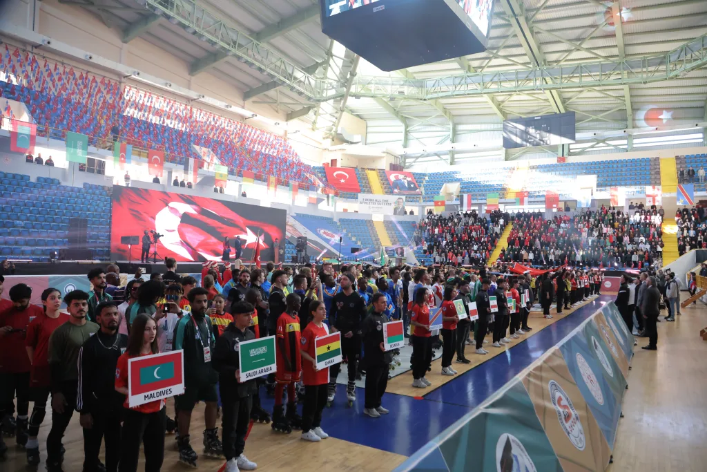 National delegations lined up with their flags in a full arena at the Football Skating World Cup 2024